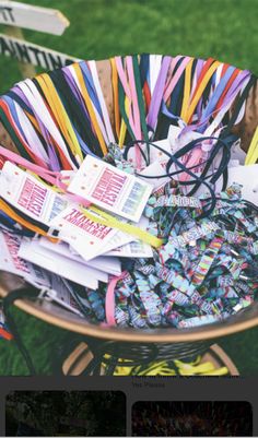 a basket filled with lots of different colored ribbons on top of a wooden chair in the grass