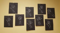 six hand signals drawn on black paper in front of a yellow wall with chalk writing