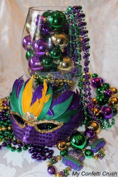 a glass vase filled with lots of purple and green beads