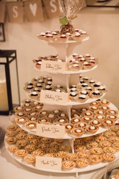 a tiered tray with cupcakes and pastries on it is displayed at a wedding reception