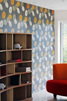 an orange chair sitting in front of a bookshelf next to a large window