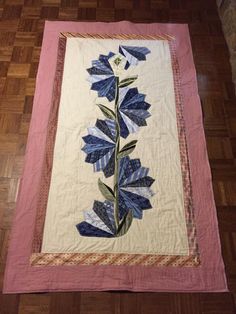 a quilted wall hanging with blue flowers on it