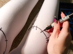 a woman is writing on her leggings with a marker and pen in front of her