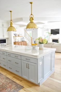 a large kitchen island with two gold pendant lights over it's white countertops