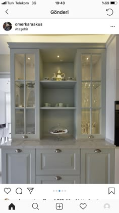 a kitchen with white cabinets and glass shelves