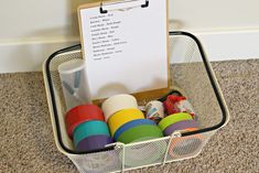 a basket filled with lots of toys on top of a carpeted floor next to a white board