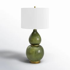 a green lamp sitting on top of a white table next to a white lampshade