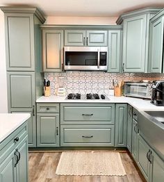 a kitchen with green cabinets and white counter tops