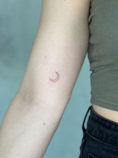 a woman's arm with a small crescent tattoo on the left side of her arm