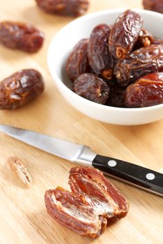 some raisins and a knife on a cutting board next to a bowl of raisins