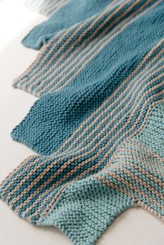 three knitted pieces of cloth laying on top of each other, one blue and the other green