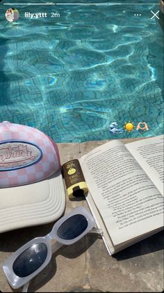 an open book, sunglasses and hat next to a swimming pool with the sun reflecting on it