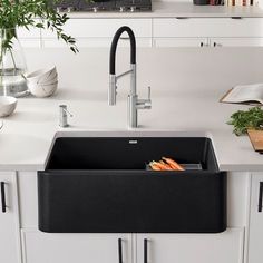 a kitchen sink with carrots in it and a black faucet on the counter