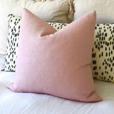 two pink pillows sitting on top of a bed next to each other with black and white designs