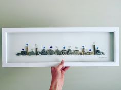 a person holding up a shadow box with rocks in it