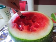 someone cutting into a watermelon with a knife