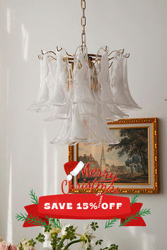 a chandelier hanging from the ceiling with merry christmas sale sign below it and flowers in vases