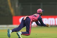 two men in pink and blue uniforms are playing cricket