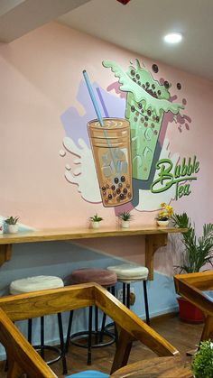 the interior of a coffee shop with tables and stools in front of a painted wall