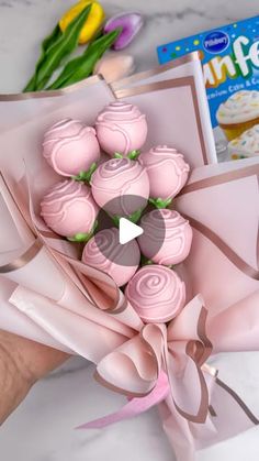 a hand holding a bouquet of pink cupcakes