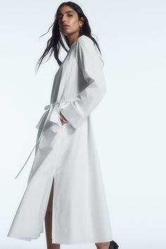 This season, the COS womenswear team reimagine the perennial shirt dress. Crafted from lightweight cotton poplin, it's cut to hit at the ankle and designed with a collarless neckline and an overlapping storm flap detail at the back that borrows from classic trench coats. It's detailed with an elasticated gathered back panel and tonal belt that allows you to personalise the shape. Relaxed fitButton closureSide slits Shell: 100% Cotton (excluding trims) / Machine wash Back length of size EU 36 is 122.3cm / Model wears a size EU 36 Chic Cotton Maxi Shirt Dress, Chic Long Cotton Shirt Dress, Relaxed Fit Maxi Shirt Dress For Daywear, Spring Workwear Maxi Dress With Side Slits, Summer Workwear Maxi Dress, Cotton Maxi Length Shirt Dress For Daywear, Summer Workwear Long Maxi Dress, Cotton Maxi Shirt Dress For Daywear, Long Summer Maxi Dress For Work