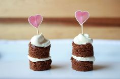 two cupcakes with white frosting and pink hearts on top