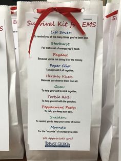 three white bags with red ribbon tied around them and some writing on the bag says survival kit ems