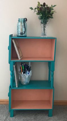 a blue shelf with some pens and pencils on it next to a flower vase