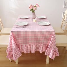 the table is set for two with plates and pink flowers in a vase on top