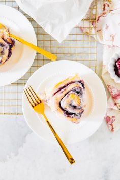 two white plates topped with food next to each other on a table and gold utensils