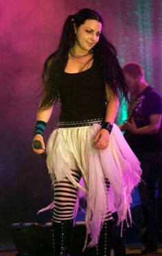 a woman in black shirt and white skirt on stage