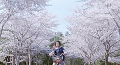 a woman riding a bike down a street next to trees with white flowers on them