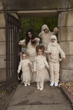 a group of people dressed in costumes standing next to each other on a sidewalk near an iron gate