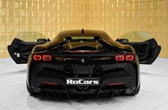 the rear end of a black and gold sports car in a showroom with yellow walls