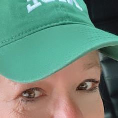 a close up of a person wearing a green hat with the word nice on it