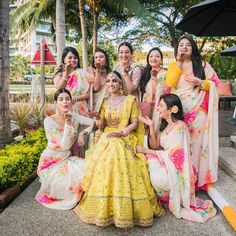 a group of women dressed in yellow and pink outfits posing for a photo with each other