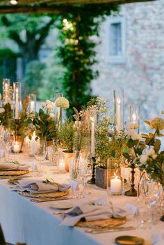 the table is set with candles, flowers and greenery for an elegant wedding reception