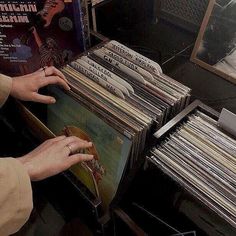 a woman is looking at records in a record store display case and reaching for them