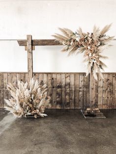 an arrangement of dried flowers on display in front of a wooden wall with planks