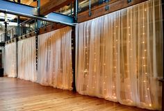 an empty room with curtains and lights on the wall, in front of a wooden floor