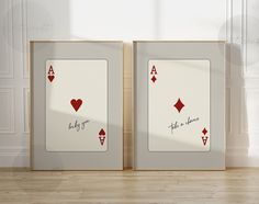 two frames with playing cards on them in front of a white wall and wooden floor