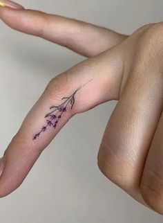 a woman's hand with a small tattoo on the left side of her finger