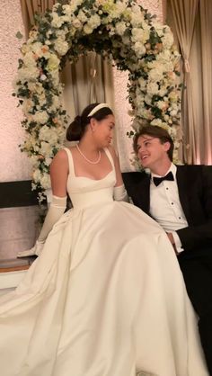 a woman in a wedding dress sitting next to a man wearing a tuxedo