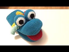 a crocheted blue toy with two eyes on it's head sitting on top of a table