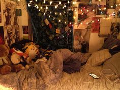 there are many stuffed animals on the bed in this room with christmas lights strung overhead