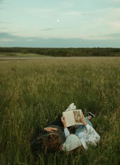 a person laying in the grass reading a book