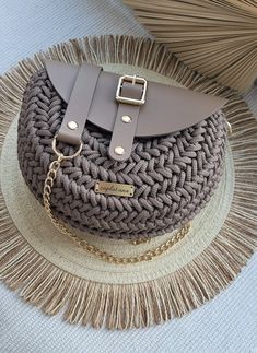 a straw hat with a chain around it on top of a table next to a purse