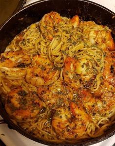 a pan filled with pasta and shrimp on top of a stove