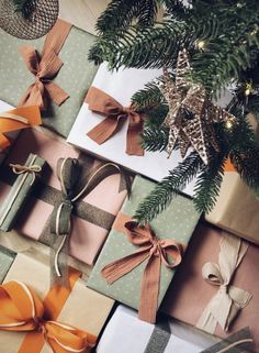 presents wrapped in brown and white paper with bows on them next to a christmas tree