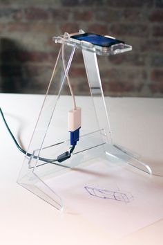 a cell phone is plugged into an electronic device on a table with a brick wall in the background